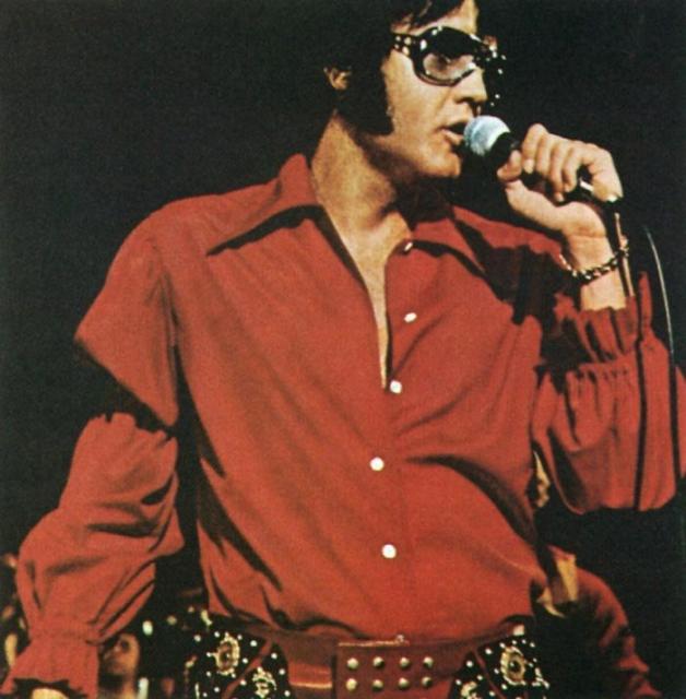 Elvis in red shirt wearing big sunglasses
