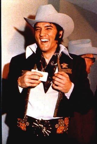 Elvis Presley in cowboy outfit with big smile
