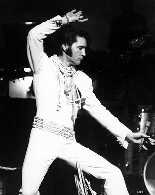 Elvis Presley on stage in white outfit
