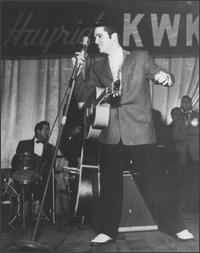 Elvis Presley singing with a cut smile
