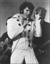 Elvis Presley wearing white outfit and singing passionately
